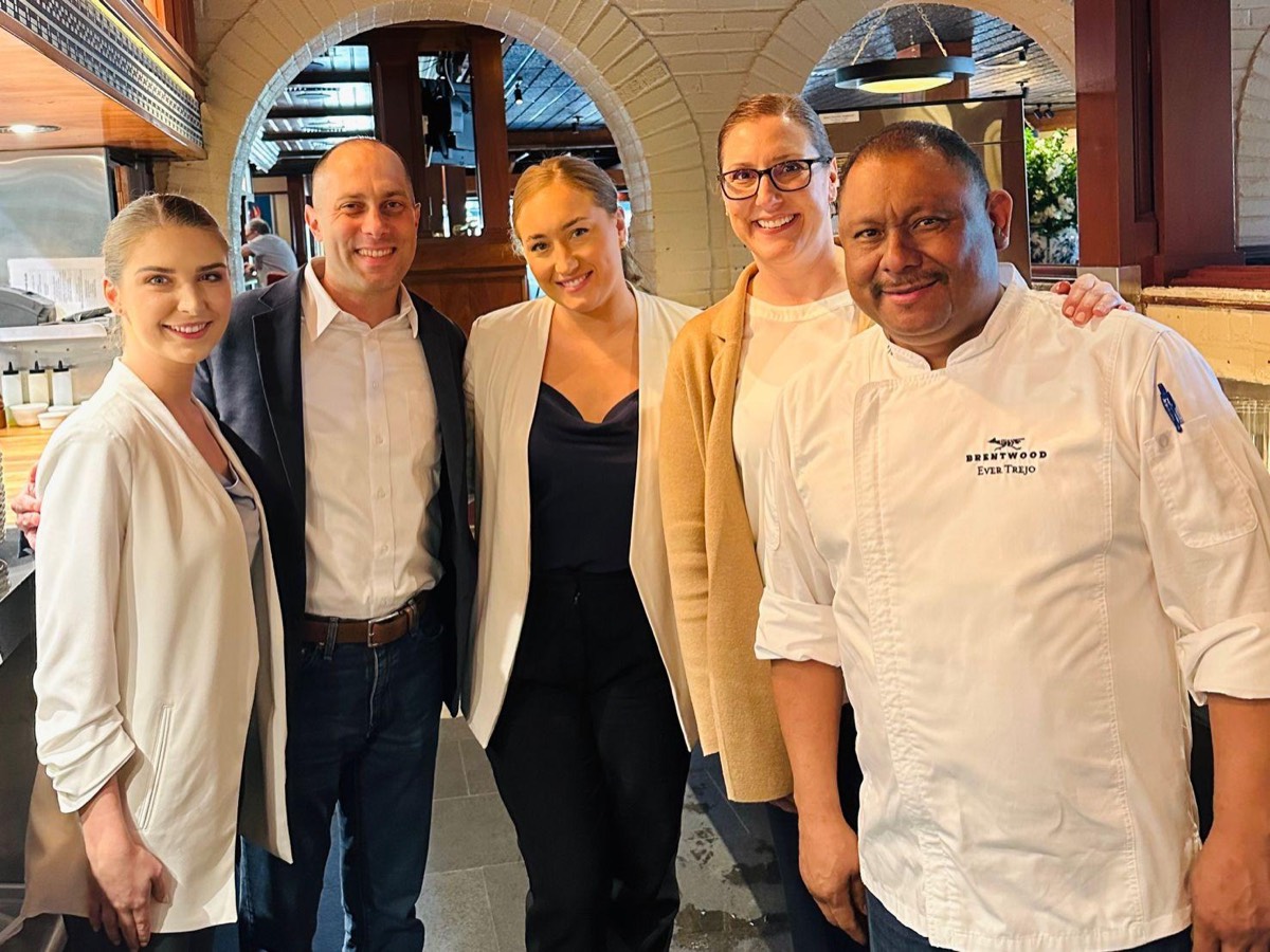 Jon Peck, in a navy jacket and white shirt, with the Brentwood managers and chef under brick archways in front of the open kitchen
