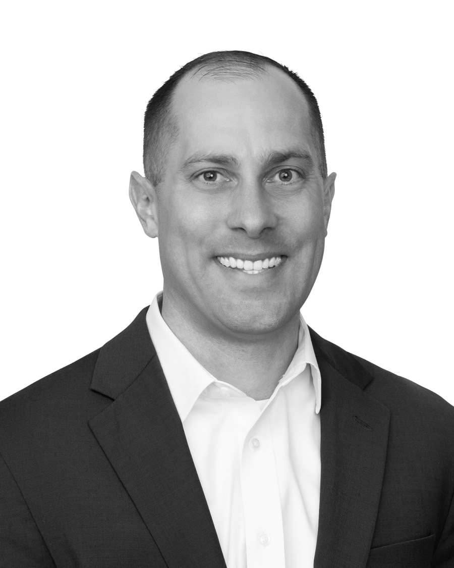 Jon Peck, black and white portrait in a dark suit and open-collared white shirt